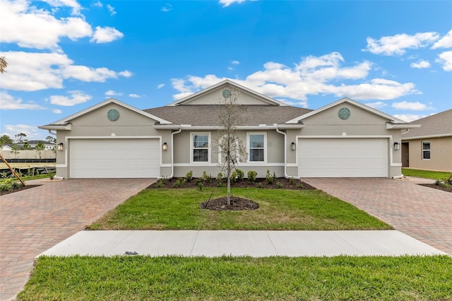 single story home with an attached garage, decorative driveway, a front yard, and stucco siding