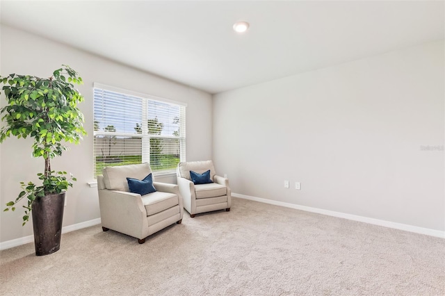 sitting room with baseboards and light colored carpet