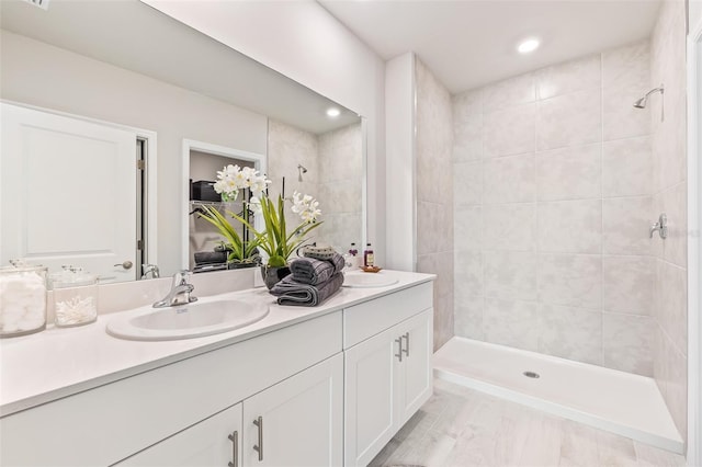 full bath featuring double vanity, a shower stall, a sink, and recessed lighting