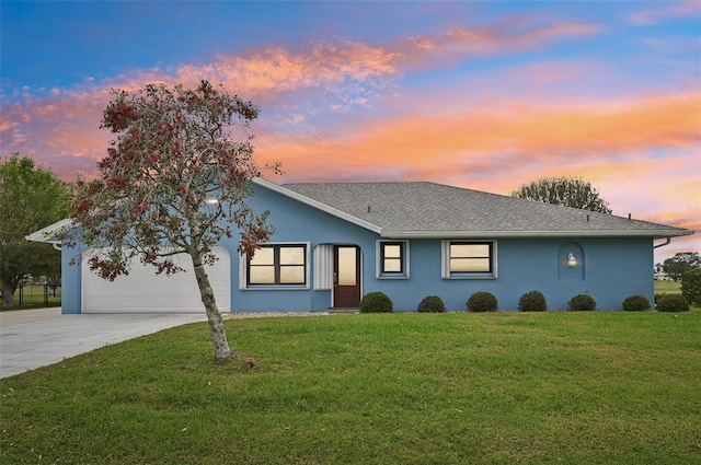 ranch-style home featuring a garage, stucco siding, concrete driveway, and a yard