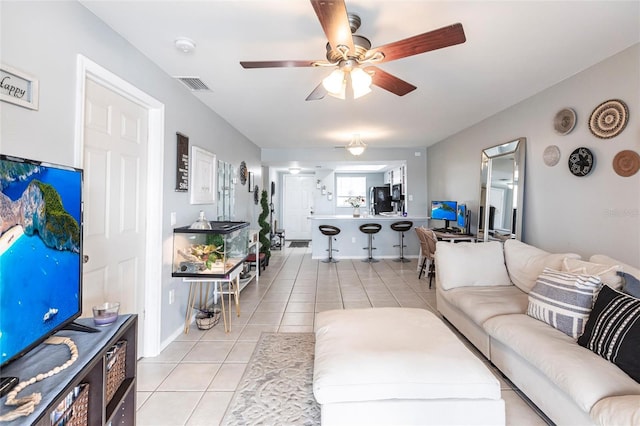 living room with light tile patterned floors, visible vents, and a ceiling fan