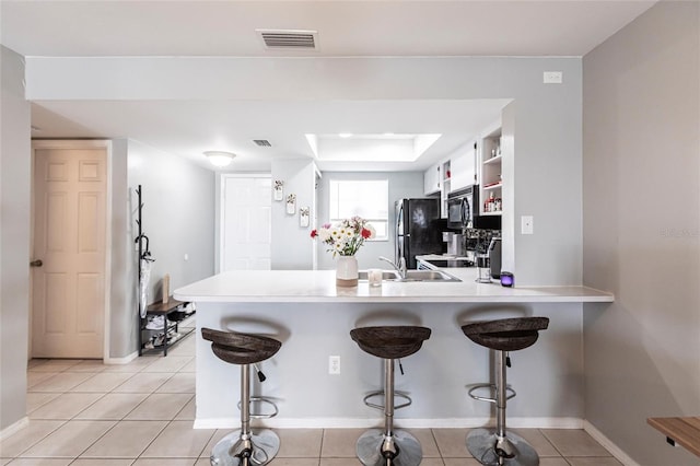 kitchen with visible vents, light countertops, white cabinetry, a peninsula, and black appliances