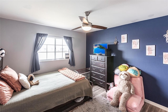 bedroom with ceiling fan, wood finished floors, and baseboards