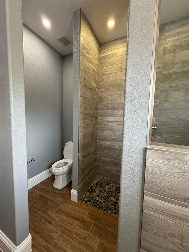 full bathroom with baseboards, a textured wall, toilet, and wood tiled floor