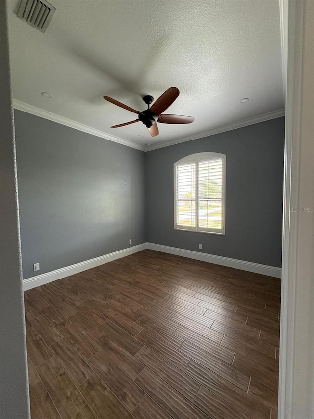 spare room featuring baseboards, dark wood-style flooring, visible vents, and crown molding