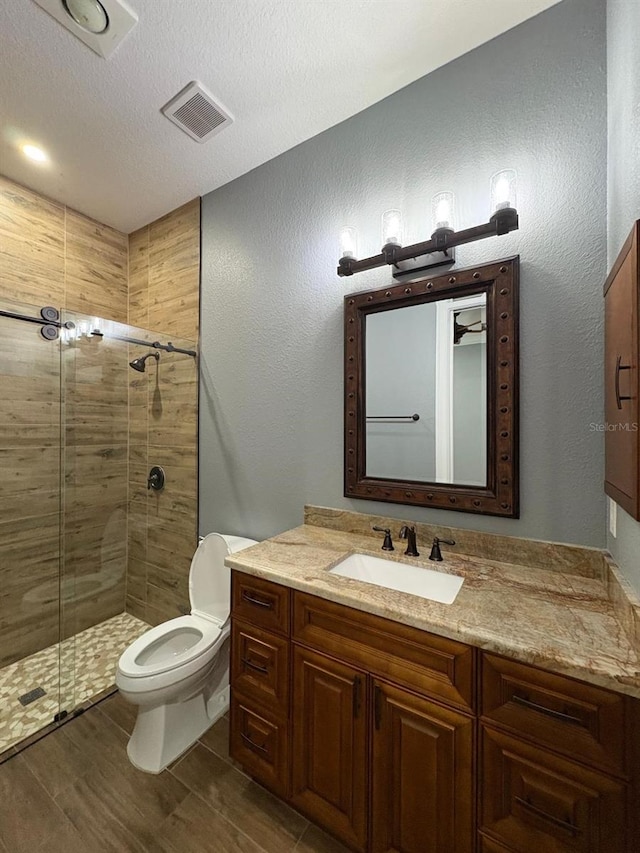 full bathroom with toilet, a stall shower, vanity, and visible vents