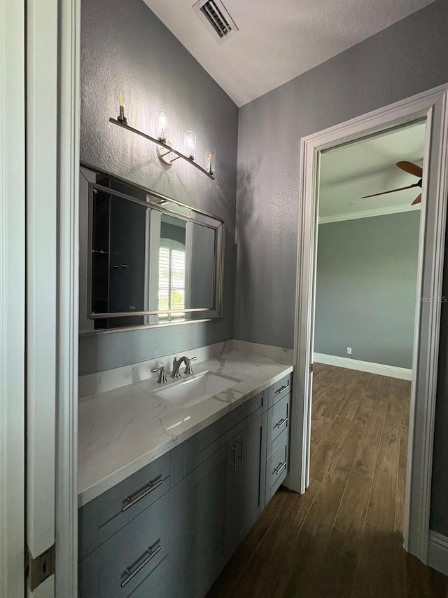 bathroom with baseboards, visible vents, ceiling fan, wood finished floors, and vanity