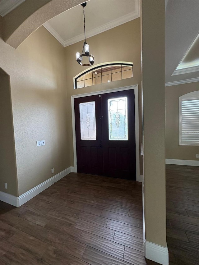 foyer entrance featuring dark wood-style floors, baseboards, crown molding, and an inviting chandelier