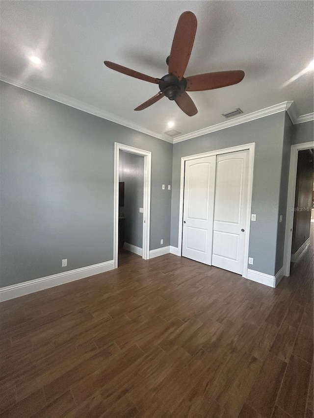 unfurnished bedroom featuring dark wood-style flooring, visible vents, crown molding, and baseboards