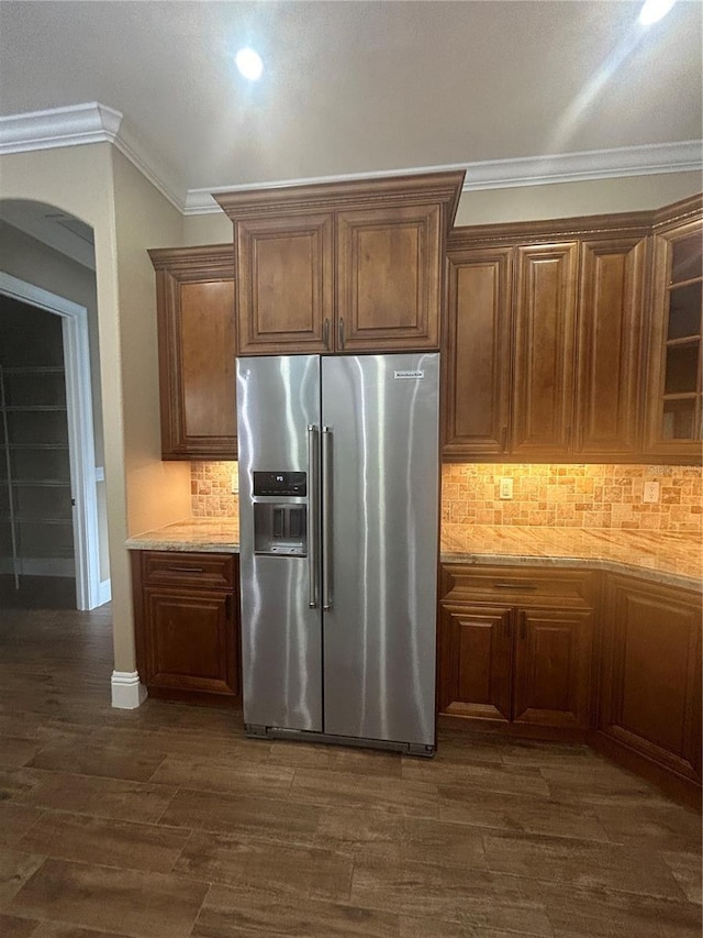 kitchen with ornamental molding, dark wood-style flooring, high end refrigerator, and light stone countertops