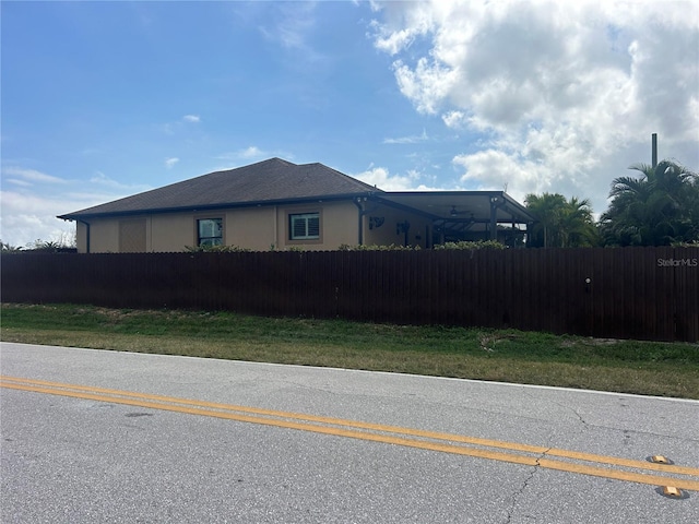 view of side of home featuring fence and stucco siding