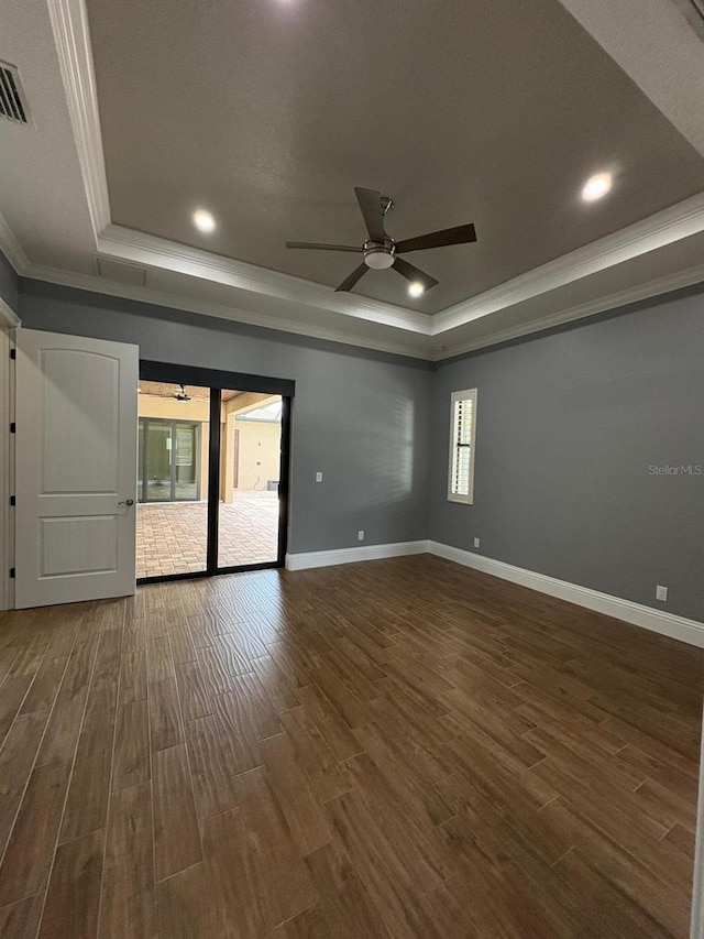 spare room featuring a tray ceiling and dark wood finished floors