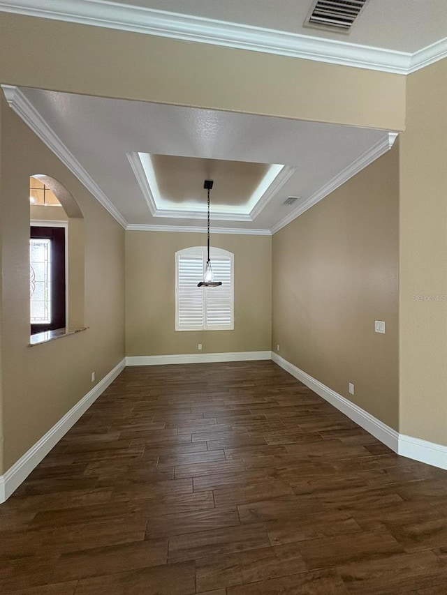 interior space with visible vents, baseboards, ornamental molding, dark wood-style floors, and a tray ceiling