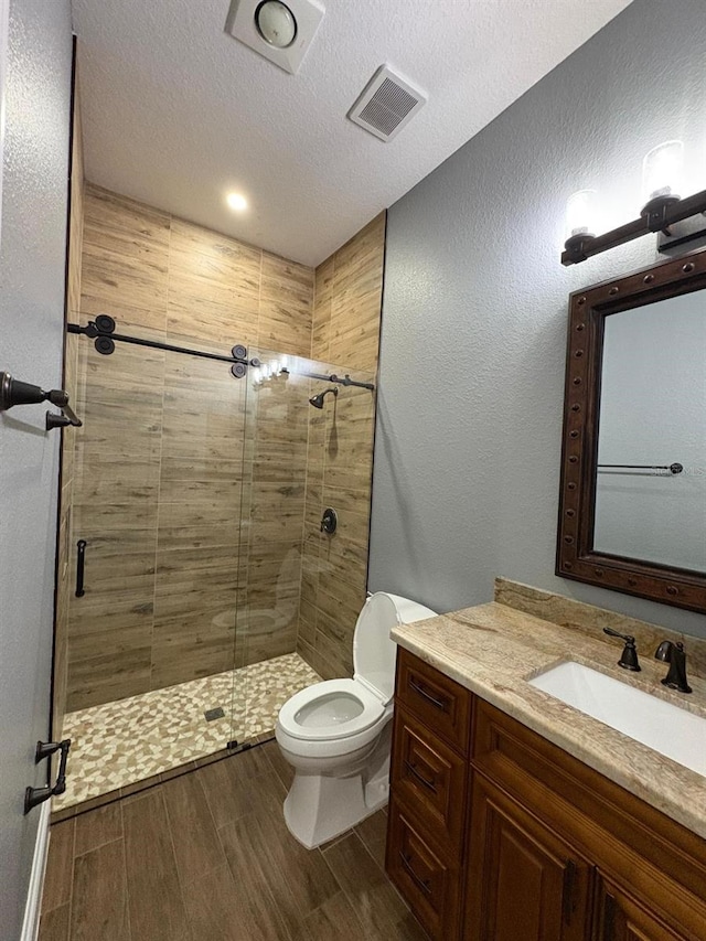 full bathroom with toilet, a stall shower, wood tiled floor, and visible vents