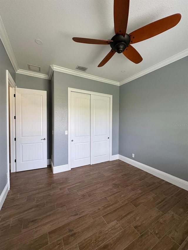 unfurnished bedroom with crown molding, a closet, visible vents, and dark wood-type flooring