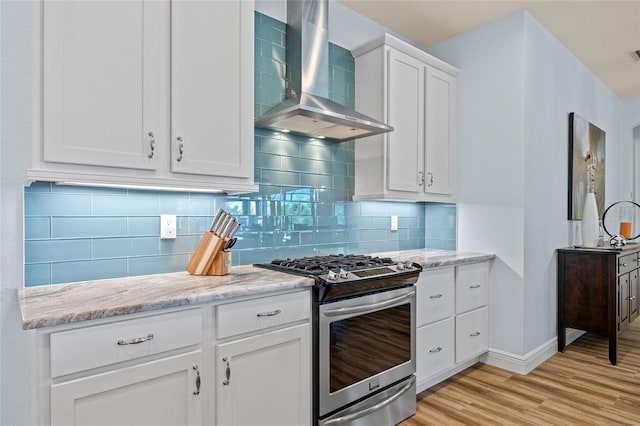 kitchen featuring light wood-style flooring, white cabinetry, backsplash, wall chimney exhaust hood, and stainless steel range with gas stovetop