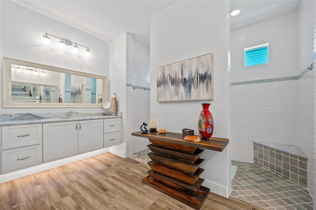 bathroom with a walk in shower, wood finished floors, and vanity