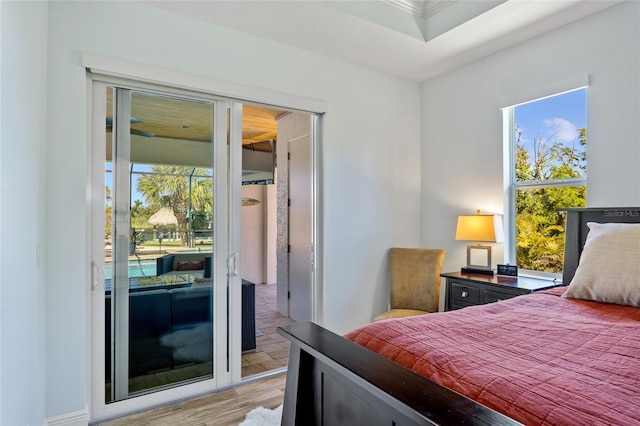 bedroom with light wood finished floors, multiple windows, and access to exterior