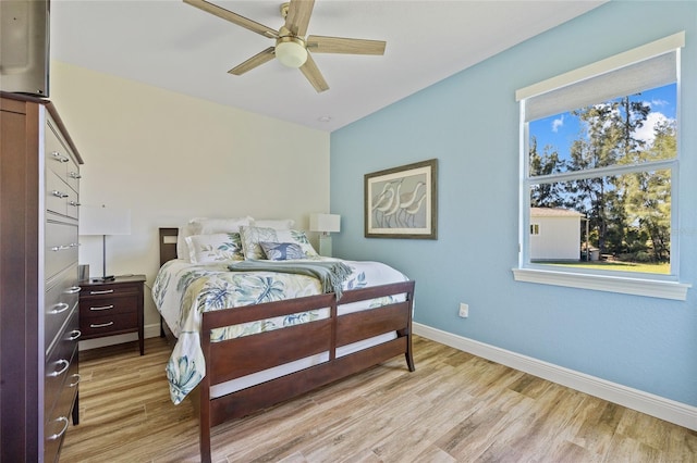 bedroom with light wood-style flooring, multiple windows, baseboards, and ceiling fan