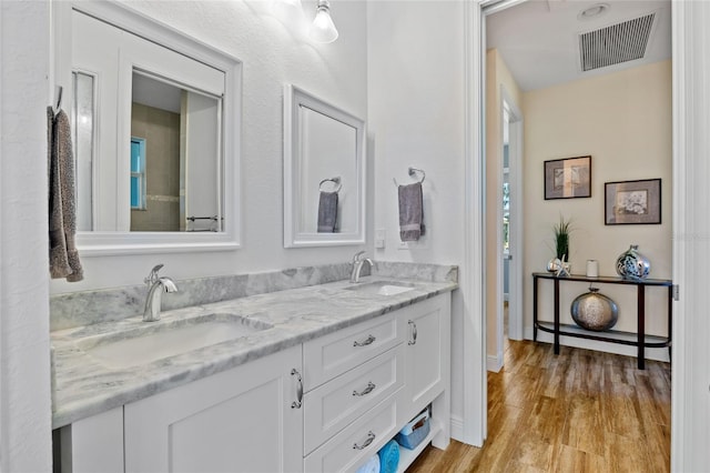 bathroom with double vanity, visible vents, a sink, and wood finished floors