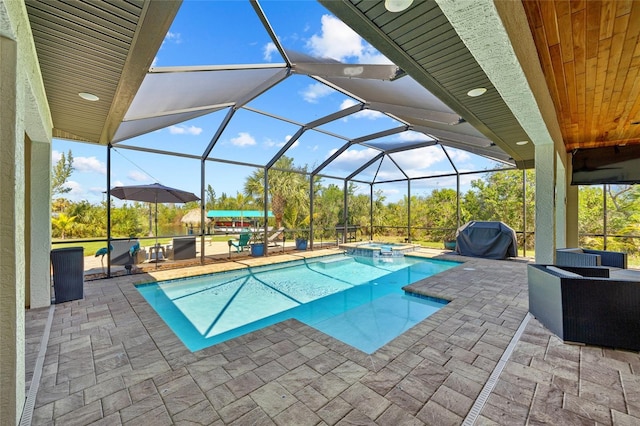 view of swimming pool featuring a lanai, a grill, a pool with connected hot tub, and a patio