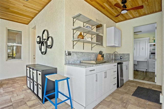 kitchen featuring a ceiling fan, wooden ceiling, a textured wall, and open shelves