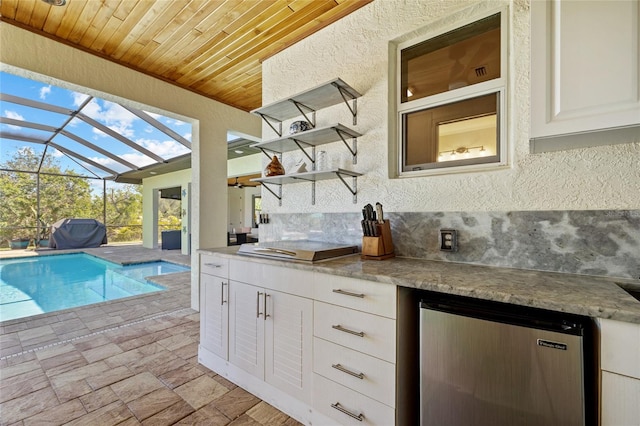 kitchen featuring a textured wall, wooden ceiling, refrigerator, white cabinetry, and open shelves