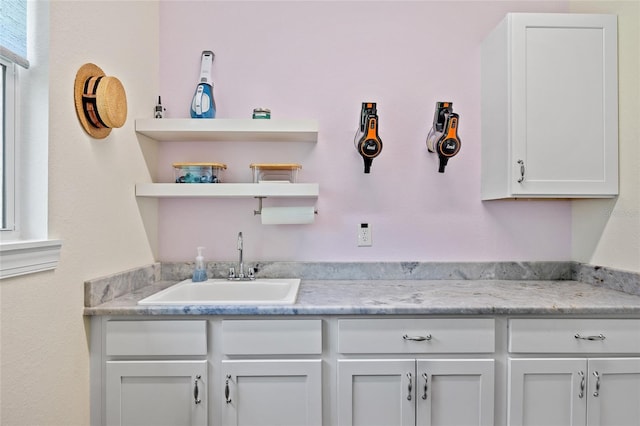 kitchen with open shelves, a sink, light countertops, and white cabinetry