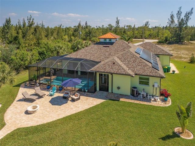 rear view of house with a fire pit, an outdoor pool, glass enclosure, a yard, and a patio area