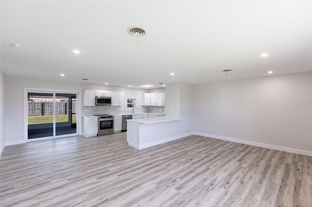 kitchen featuring appliances with stainless steel finishes, open floor plan, light countertops, and tasteful backsplash