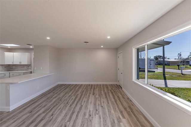 unfurnished living room featuring light wood-style floors, recessed lighting, and baseboards