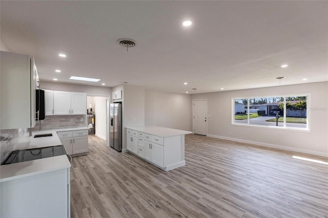 kitchen featuring light countertops, light wood-type flooring, stainless steel fridge, and visible vents