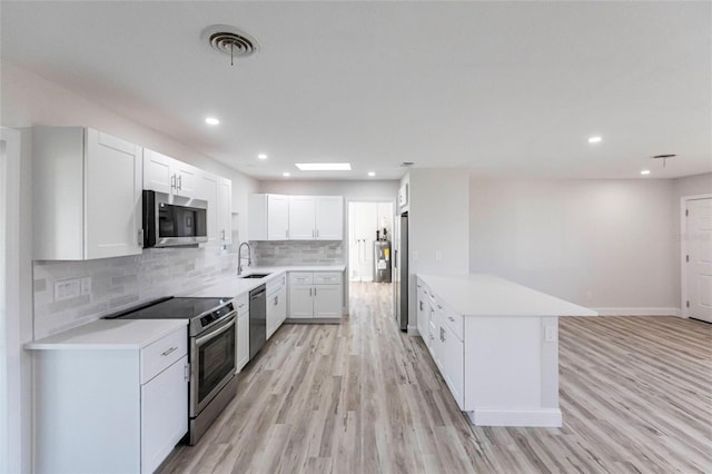 kitchen featuring stainless steel appliances, light countertops, visible vents, backsplash, and a sink