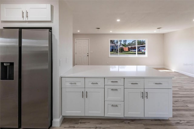 kitchen with light wood finished floors, white cabinets, stainless steel fridge with ice dispenser, light countertops, and recessed lighting