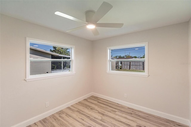 spare room featuring ceiling fan, light wood finished floors, and baseboards