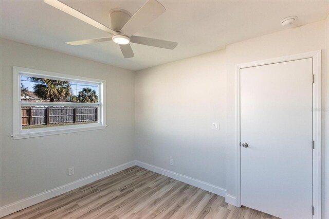 unfurnished bedroom with ceiling fan, light wood finished floors, and baseboards