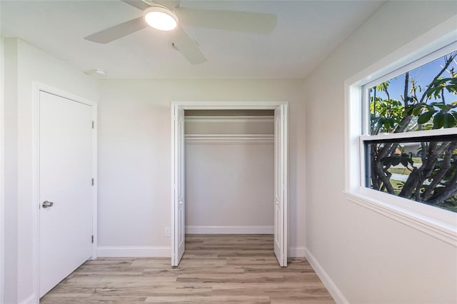 unfurnished bedroom featuring light wood finished floors, a ceiling fan, baseboards, and a closet