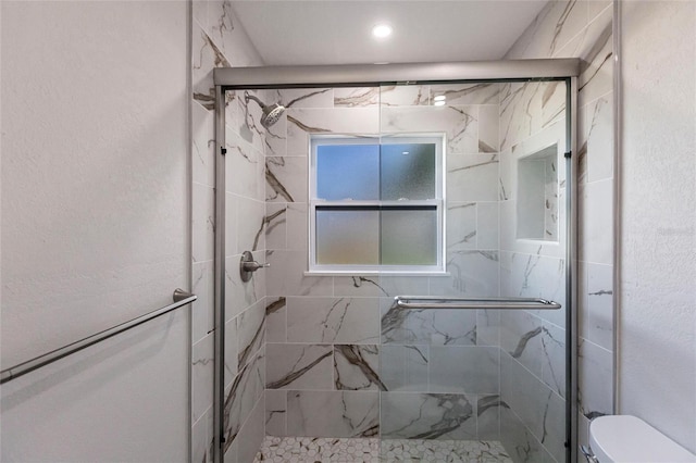 full bathroom featuring a stall shower, a textured wall, and toilet