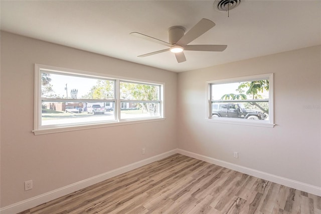 empty room featuring ceiling fan, light wood-style floors, visible vents, and baseboards