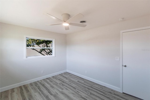 spare room featuring a ceiling fan, wood finished floors, visible vents, and baseboards