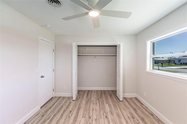 unfurnished bedroom featuring a closet, visible vents, light wood-style flooring, ceiling fan, and baseboards