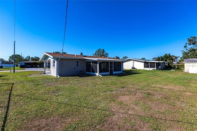 rear view of property featuring a sunroom and a lawn