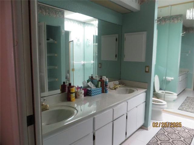 bathroom with toilet, a shower stall, double vanity, and a sink