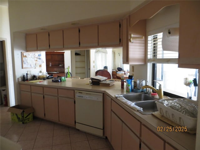 kitchen with dishwasher, light countertops, a peninsula, and a sink