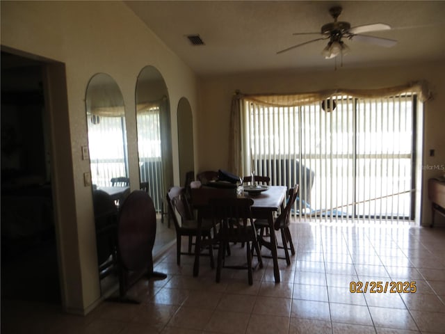 tiled dining room with ceiling fan, plenty of natural light, arched walkways, and visible vents