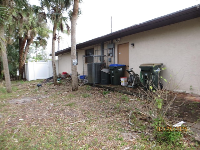 back of house with fence, cooling unit, and stucco siding