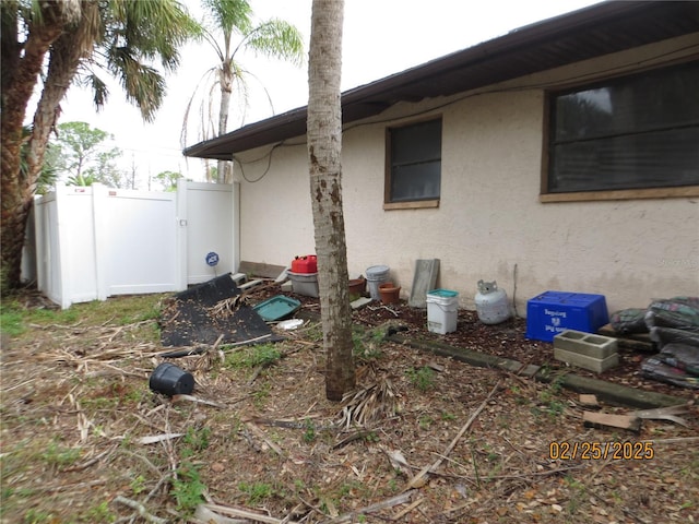 view of side of property with fence and stucco siding