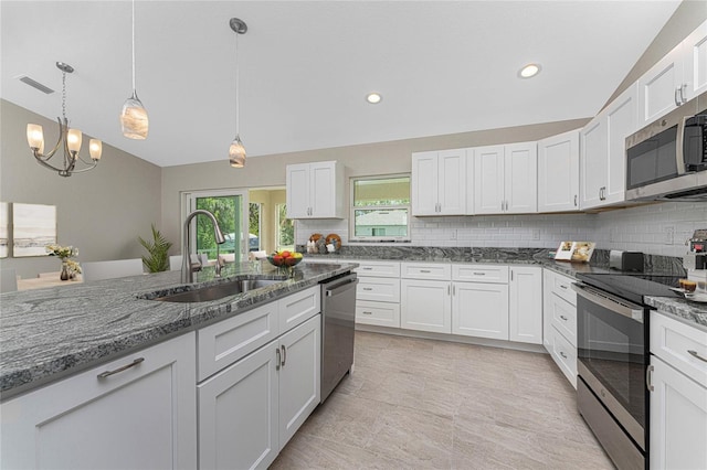 kitchen featuring tasteful backsplash, appliances with stainless steel finishes, white cabinets, a sink, and dark stone countertops