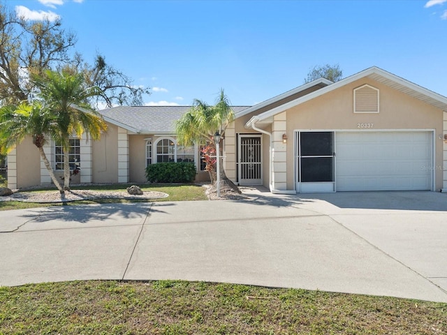 single story home featuring a garage, concrete driveway, and stucco siding