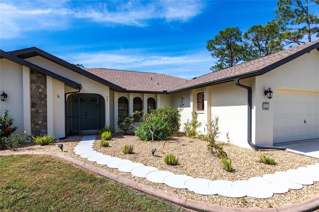 ranch-style home featuring a garage, stone siding, roof with shingles, and stucco siding